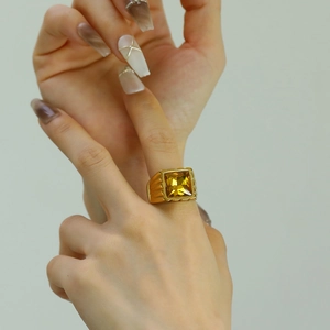 Close-up of a gold stainless steel ring featuring a large square yellow gemstone on hand