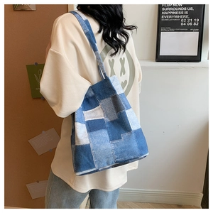 Detailed view of casual blue denim patchwork tote bag styled on a model shoulder