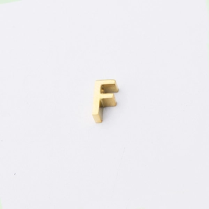 Detailed view of mirror polished gold stainless steel letter F bead for jewelry making