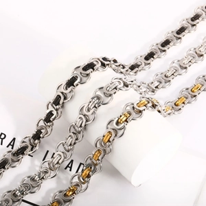 Detailed close-up of woven stainless steel Byzantine chains in silver, black, and gold tones