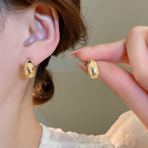 Detail showing high-polish 18K gold-plated teardrop stud earrings worn on ear