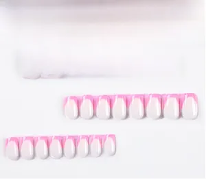 Detail view of pink French tip press-on nails in various sizes with a square-oval shape