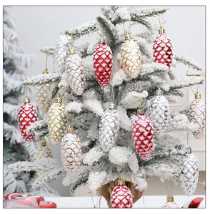 Detail of colorful painted pine cone ornaments hanging on a snowy Christmas tree branch