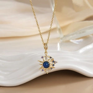 Macro shot of sun and moon pendant with blue stone on white ceramic and silk