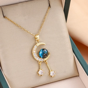 Gold celestial necklace with zircon crescent moon and blue star sphere pendant in a jewelry box