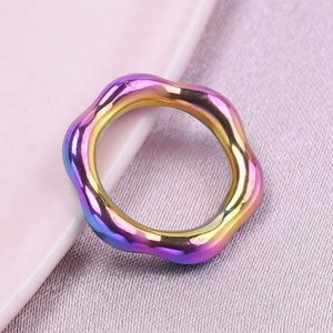 Detailed macro shot of an iridescent wavy stainless steel ring on a pink ceramic tray