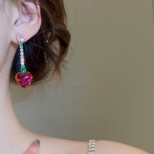 Close-up of heart-shaped red zircon earrings with colorful tassel chain on a model