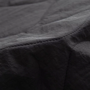 Macro detail of high-quality windproof black fabric with precise quilting stitches