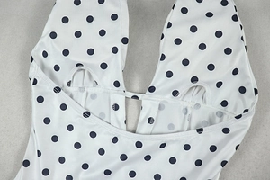 Detail of V-neckline and stitching on a white polka dot sleeveless dress fabric