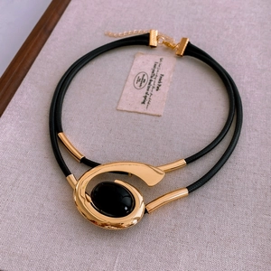Detail of double-layer black cord necklace featuring a fluid gold pendant and black gemstone