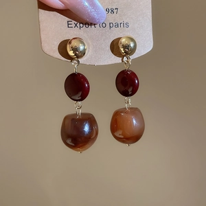 Detail of vintage resin drop earrings with amber texture and gold stud on card