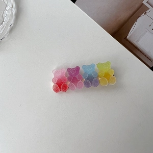 Macro detail of gummy bear hair clips in gradient resin pink, purple, blue, and yellow-green