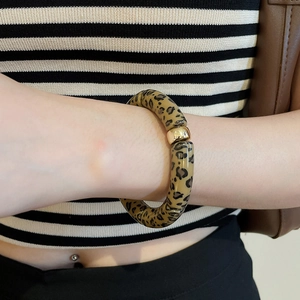 Close-up of leopard print resin bangle featuring a gold accent bead on wrist