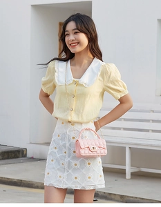 Pink quilted PVC jelly bag with metal chain and woven handle on model in floral dress