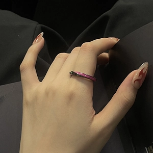 Close-up of dark metal ring with pink enamel stars on hand with flame nail art