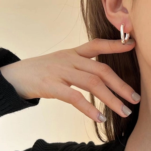 Close-up of a model wearing high-polish silver U-shaped hoop earrings in a minimalist style