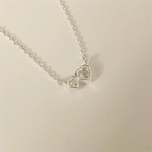 Close-up of dual heart pendants with sparkling zircons on a delicate silver chain
