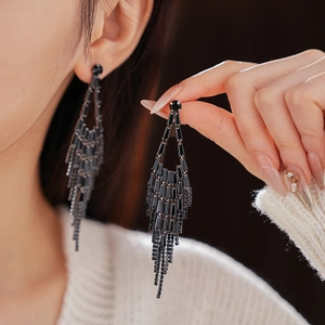 Close-up of elegant black crystal teardrop tassel earrings worn by a female model