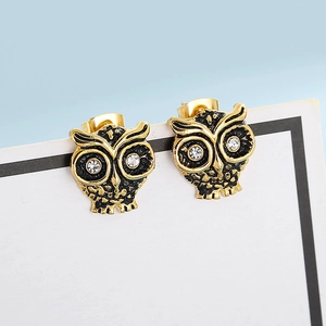 Détail macro de boucles d'oreilles chouette en or vieilli avec cristaux blancs brillants