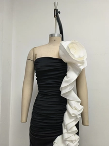 Close-up of a giant white 3D flower and layered ruffle on black strapless mermaid dress