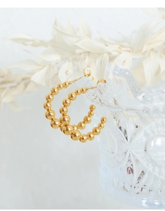 Macro detail of 18k gold plated U-shaped earrings featuring polished gradient steel beads