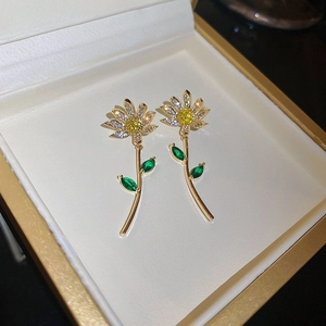Detailed macro shot of floral crystal earrings with white zircons and green gems in a box