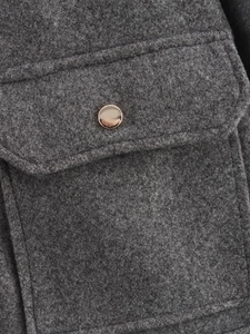 Nahaufnahme der dunkelgrauen Tweed-Struktur mit rundem Metallknopf am Taschendetail