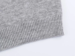 Detailed macro view of the grey knitted vest showing refined ribbed hem craftsmanship