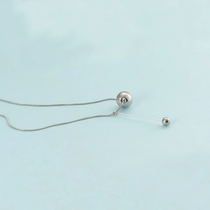 Detail of silver stainless steel ball necklace with tassel pendant on blue background