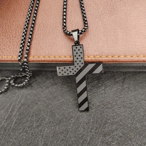 Detail of black stainless steel cross pendant with American flag pattern on chain