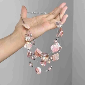 Multi-layer pink irregular stone necklace with shell accents held in hand