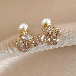 Detailed shot of gold-plated badminton earrings with crystal petals and pearl on satin