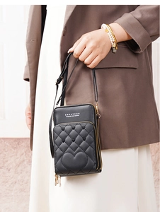 Close-up of black crossbody bag with quilted heart pattern and multi-layer zippers