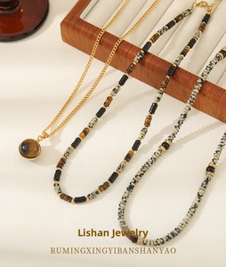 Macro shot of layered necklaces with spotted natural stones and gold tiger eye pendant
