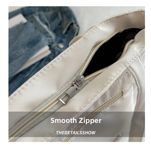 Detailed close-up of the smooth silver metal zipper on a white canvas tote bag