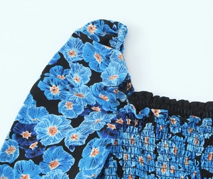Detail des elastischen Karree-Ausschnitts und der blauen Blumenärmel an einem schwarzen Kleid