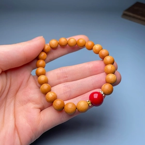 Close-up of wood bead bracelet featuring a red accent and gold rhinestone spacers