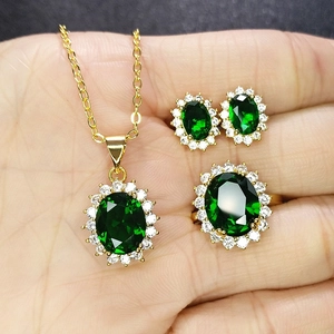 Close-up of emerald green jewelry set with necklace, ring, and earrings on hand
