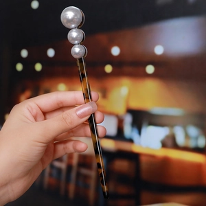 Detailed close-up of a tortoiseshell acetate hair stick with three gradient faux pearls