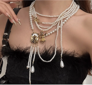 Detail of layered pearl necklace with gold angel pendants and dangling pearl tassels