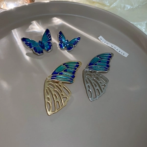Detail of hollow enamel butterfly earrings with blue crystals and gold metallic base
