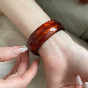 Close-up of translucent caramel resin bangle with unique fluid marble textures on wrist