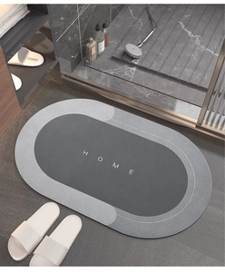 Macro detail of oval grey dual-tone absorbent bath mat with HOME text in bathroom
