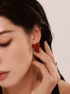 Close-up of a model wearing minimalist red heart earrings with polished enamel finish