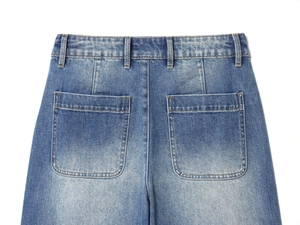 Macro shot of high-waist denim jeans featuring rear patch pockets and belt loops