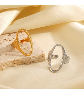 Detail of gold and silver hammered oval rings on textured stone and beige silk