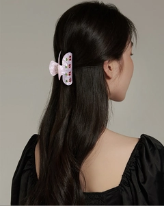 Pink acrylic cherry hair claw clip with colorful rhinestones worn on hair by a model