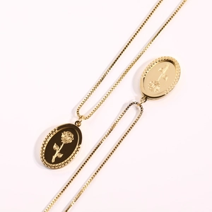 Detail of vintage gold stainless steel double oval pendants with rose engravings