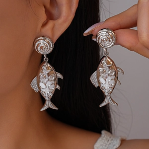 Chic silver metallic textured large fish drop earrings worn by a model in a close-up shot