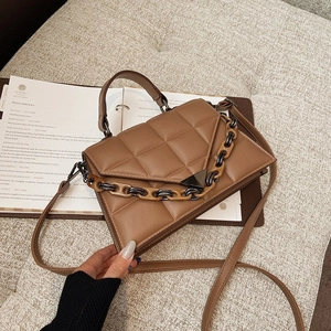 Brown quilted chain shoulder bag with triangular flap and top handle in lifestyle setting